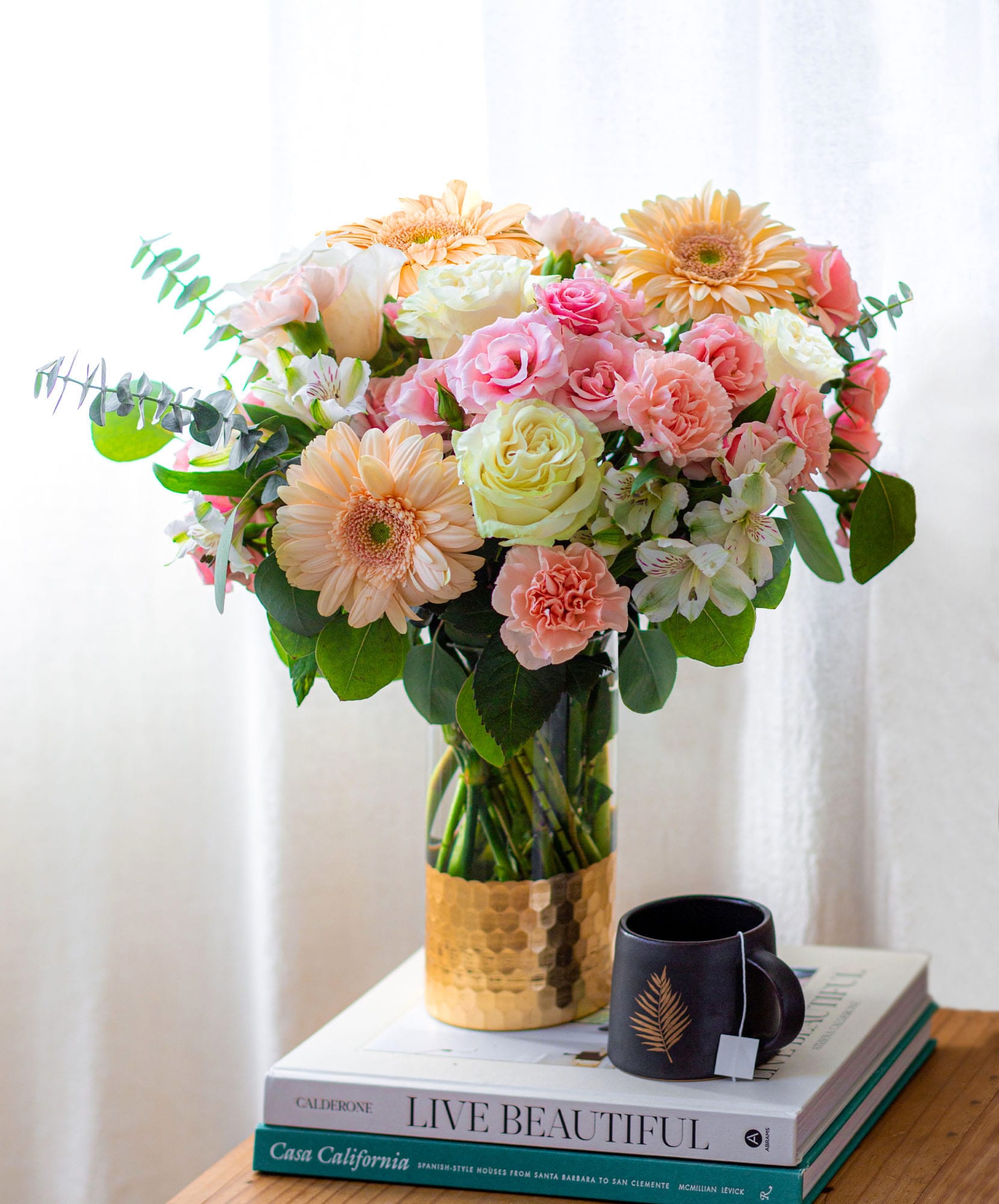 Bright and vibrant floral arrangement with pink roses, gerbera daisies, and lush greenery.